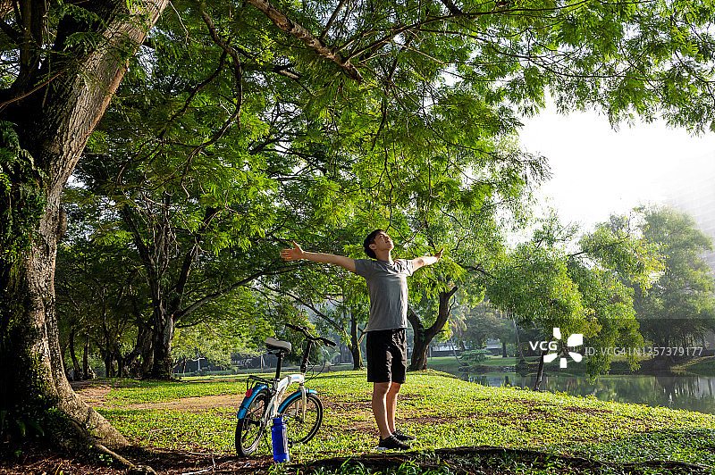 在公园里呼吸新鲜空气、伸展双臂的年轻亚裔男子图片素材
