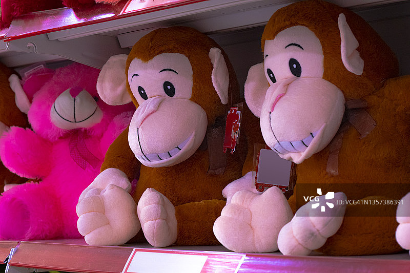 超市货架上出售的毛绒玩具，两只猴子和一只粉红色的泰迪熊图片素材