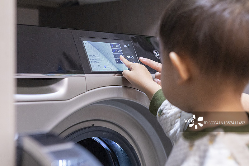 儿童使用现代洗衣机洗衣服图片素材