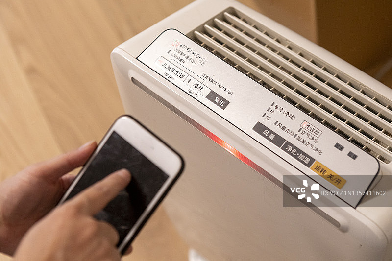 女人在家中调整空气净化器图片素材