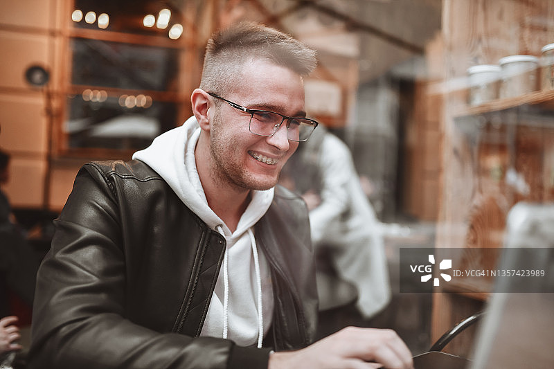 在咖啡吧用笔记本电脑工作的戴牙套微笑男子图片素材