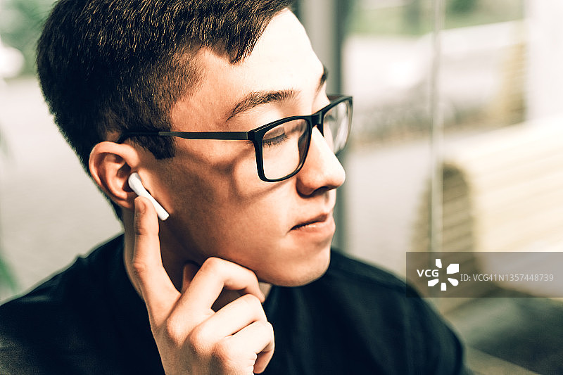 使用智能无线耳机、轻触控制传感器的亚洲男人图片素材