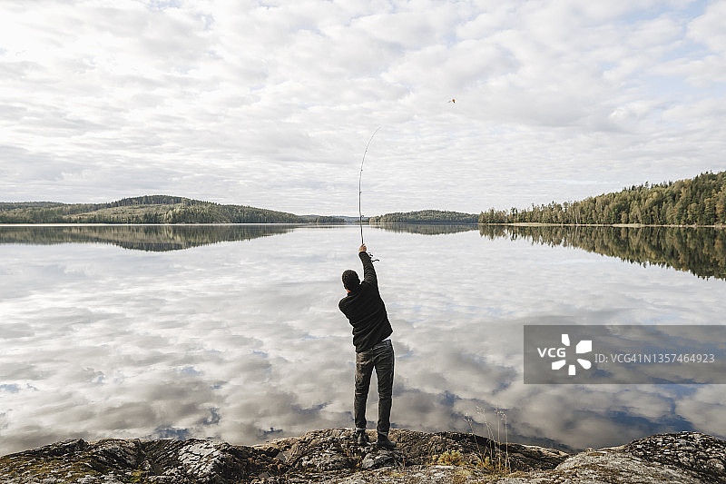 度假期间在湖中钓鱼的男人背影图片素材