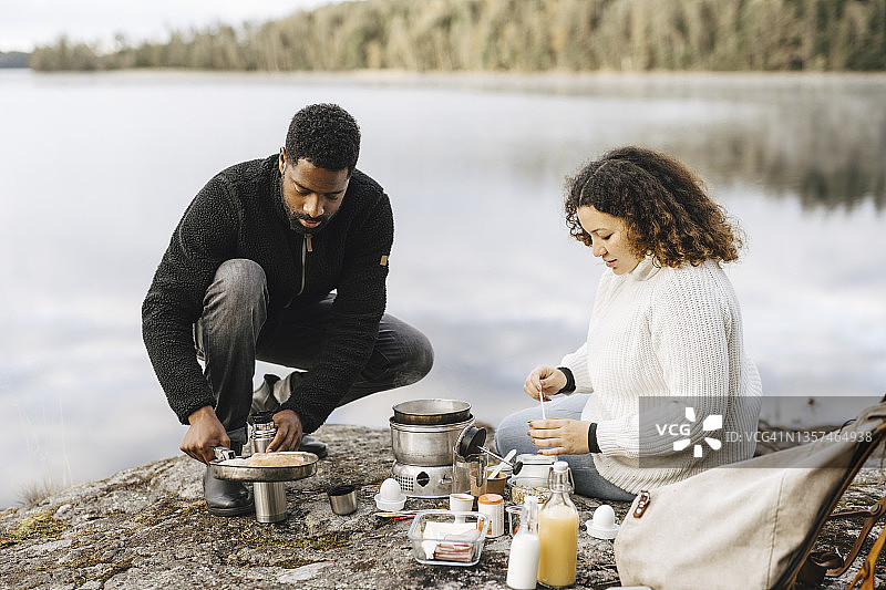 情侣在湖岸露营时准备食物图片素材