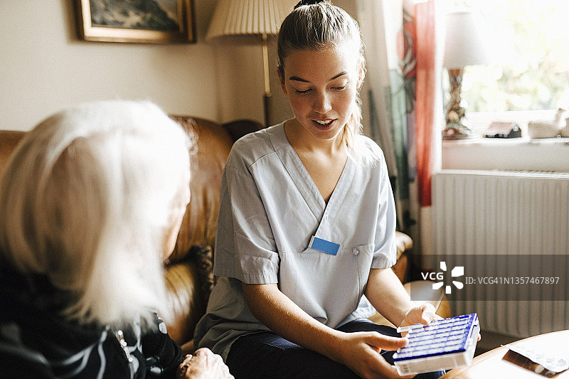 女性医护人员与老年妇女在客厅交谈，手提医药箱图片素材