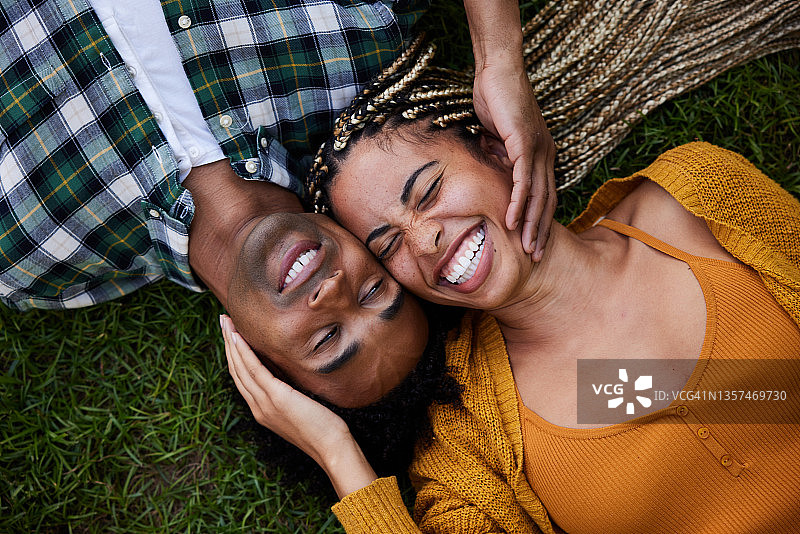 一起躺在草地上欢笑的年轻情侣图片素材