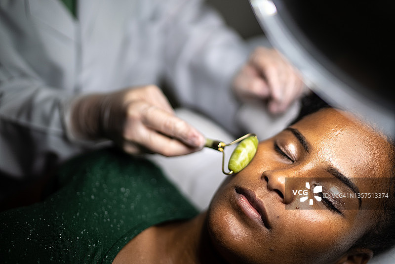 年轻女人在水疗中心接受面部按摩图片素材