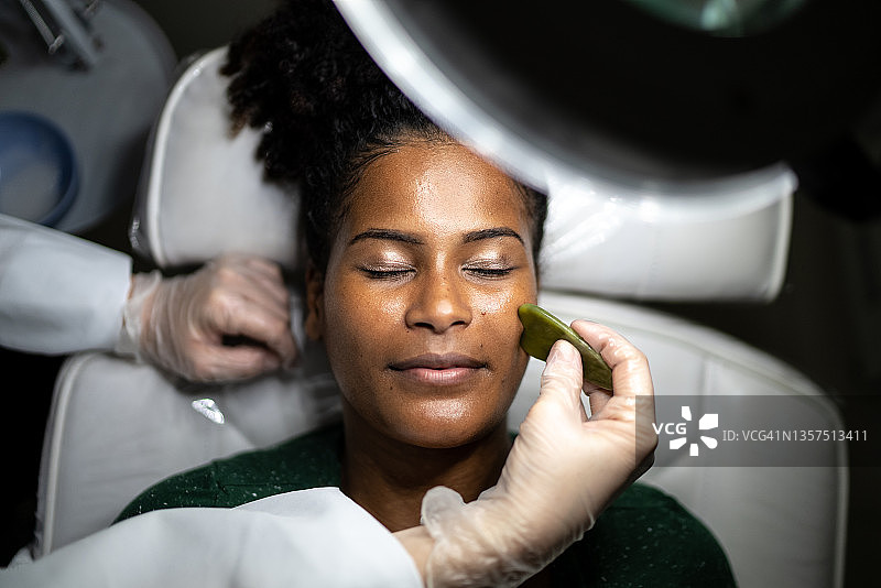 年轻女人在水疗中心接受面部按摩图片素材