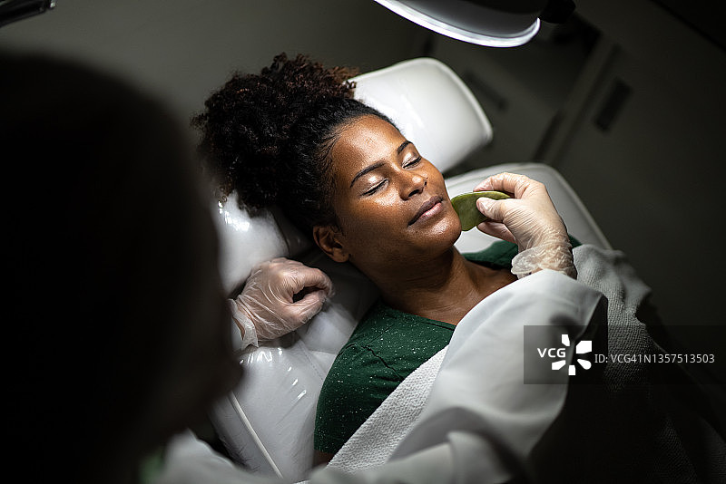 年轻女人在水疗中心接受面部按摩图片素材