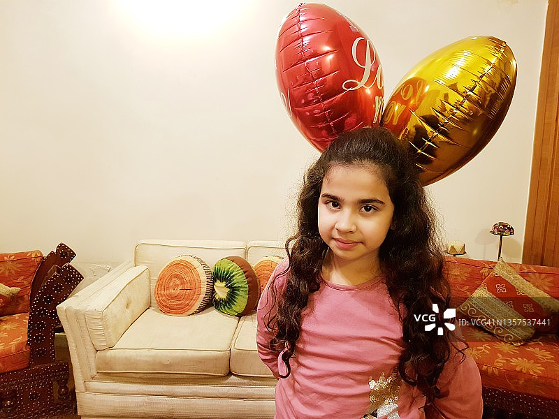 手里拿着两个氦气球看着镜头的女孩图片素材