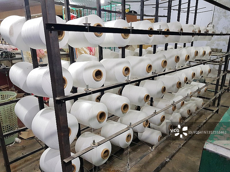 纺织厂里，一组大型白色线锥在整经机上图片素材