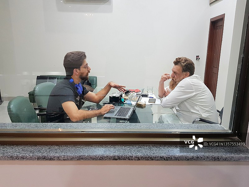 父子在办公室用笔记本电脑讨论业务图片素材