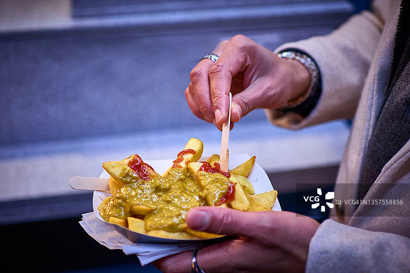 手持美味外卖薯条和咖喱酱的特写图片素材