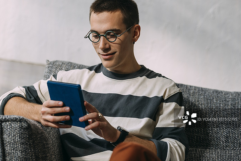 戴眼镜的帅气男人用平板电脑观看播客图片素材
