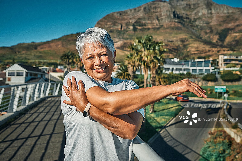 一位年长的女人在城市锻炼前独自站立伸展的照片图片素材