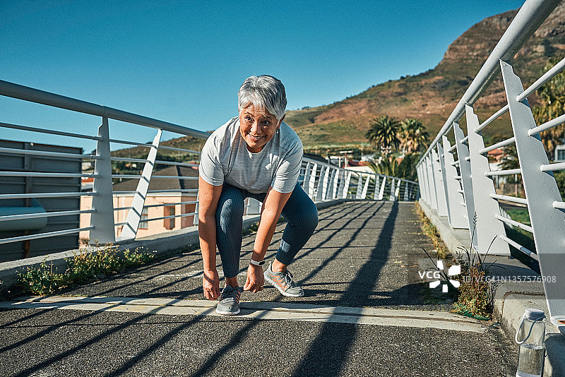 老年妇女在城市锻炼前系鞋带的全身照图片素材