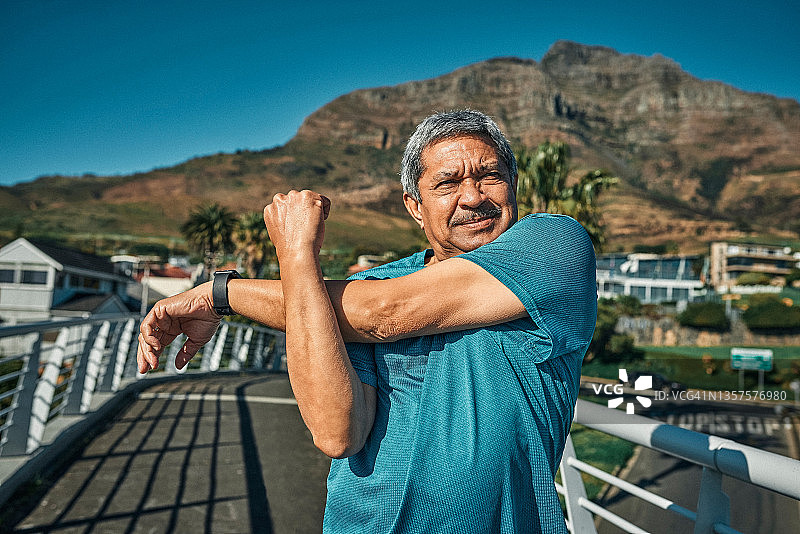 老年男人独自站在城市中，在锻炼前沉思并伸展身体图片素材