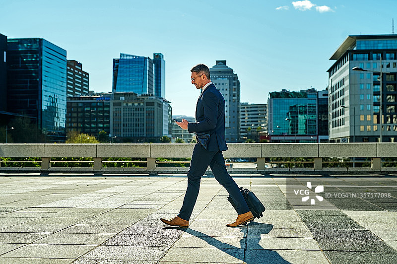 商务人士拖着行李箱在城市里行走图片素材