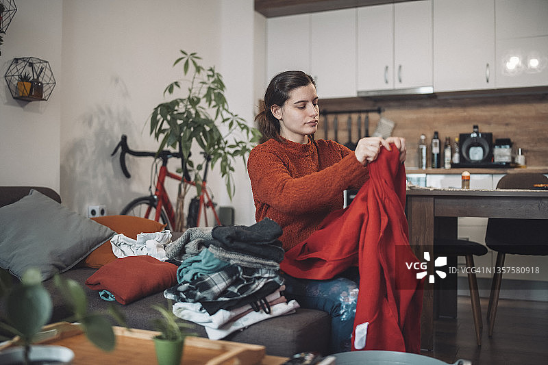 女人坐在沙发上叠衣服图片素材