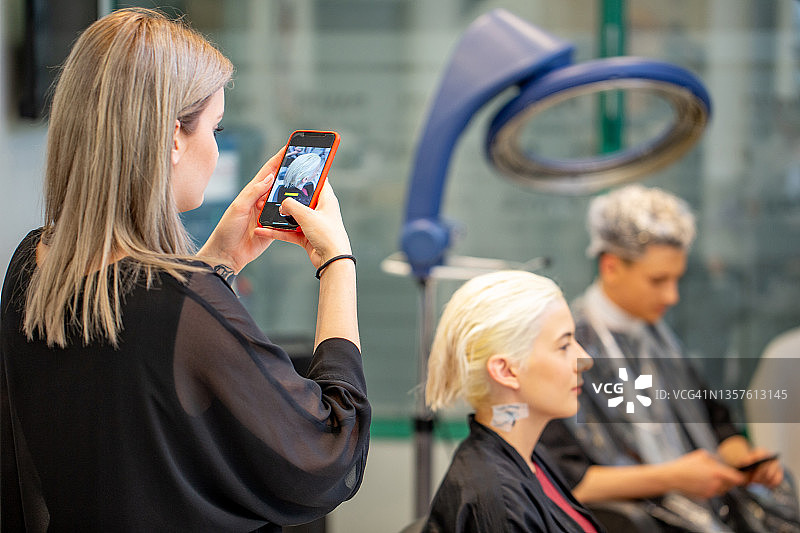 发型师用手机拍摄顾客的发型图片素材