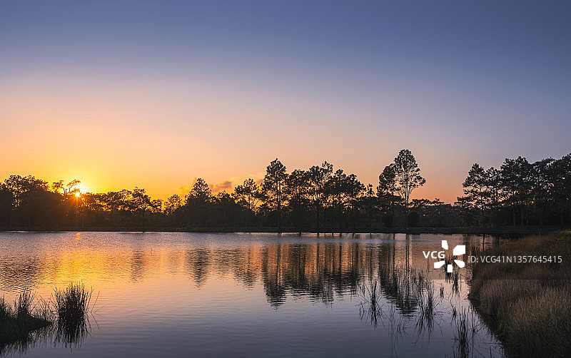 湖泊和剪影松树的日落，背景是暮光天空：泰国黎逸府Phu Kradueng冬季和雨季的自然景观图片素材
