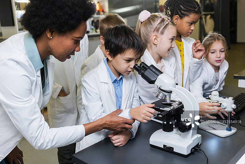 师生共同使用显微镜进行科学项目研究图片素材