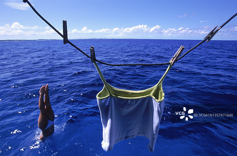 女人将衣服晾在绳子上后直接跳入海中图片素材