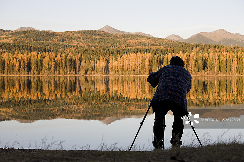男子在湖边拍摄落基山脉的秋色图片素材