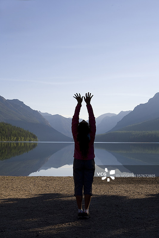 在冰川国家公园偏远湖泊练习户外瑜伽的女性剪影图片素材