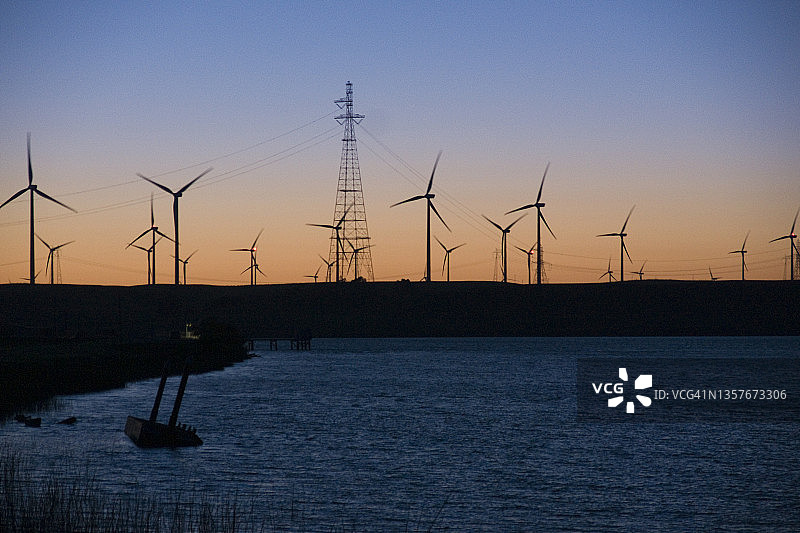 旧金山附近日落时的风力涡轮机和输电线路图片素材