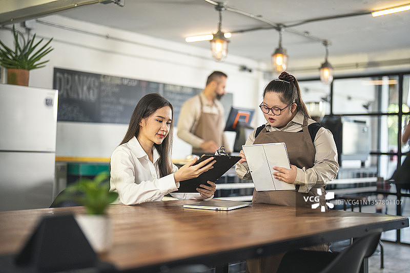 在咖啡馆工作的唐氏综合征年轻女性图片素材