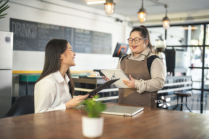 在咖啡馆工作的唐氏综合征年轻女性图片素材