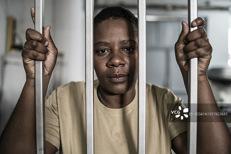 在监狱或安全门后的神情严肃和绝望的年轻非洲裔女子图片素材