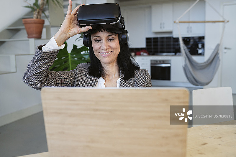 漂亮的女人在家戴着虚拟现实眼镜远程办公图片素材