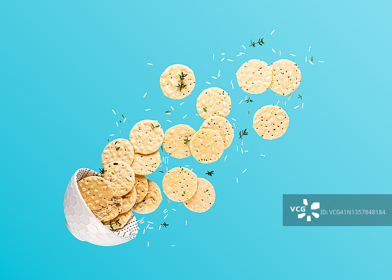 飞碗与米饼、白米和百里香枝在蓝色背景上漂浮食物构图，留有复制空间图片素材