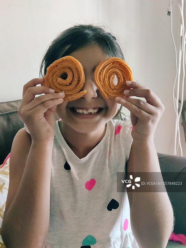 用印度小吃遮住眼睛的可爱女孩图片素材