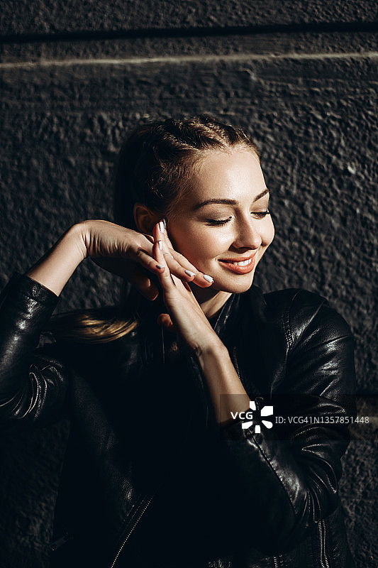 闭着眼睛的年轻女人站在黑暗的墙前图片素材