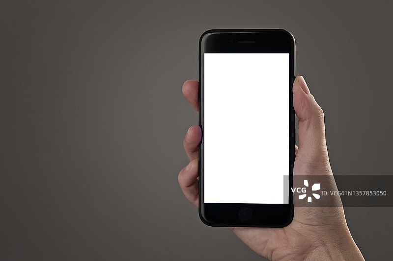 手持智能手机，灰色背景上的空白屏幕图片素材