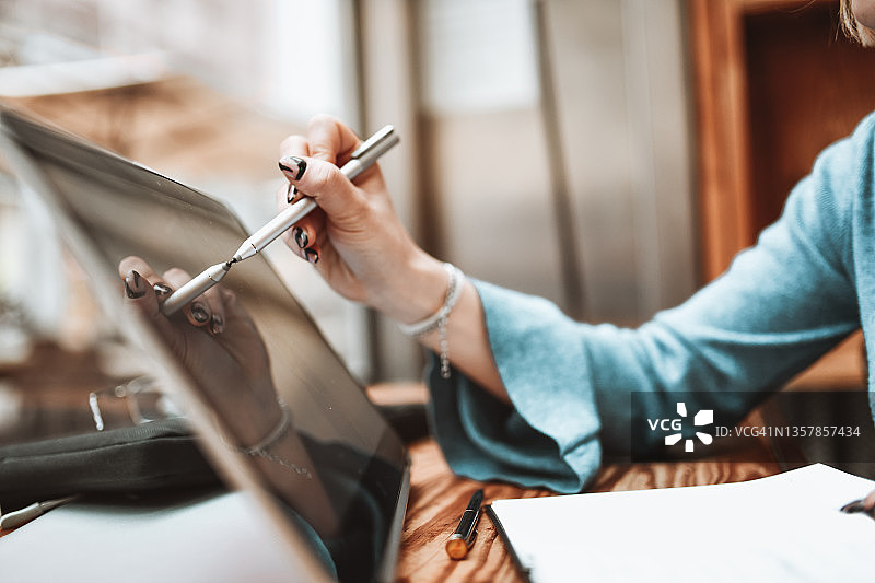 用数位笔在笔记本电脑屏幕上绘画的女性数字艺术家图片素材