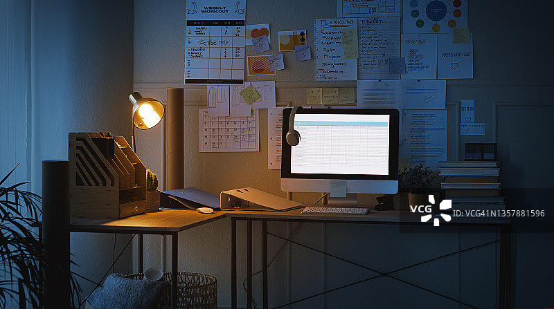 夜晚空荡的家庭办公室里书桌上的科技产品和文件图片素材