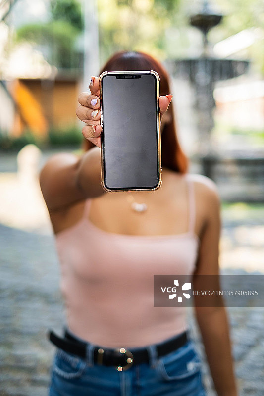 年轻拉丁裔女人展示手机屏幕特写图片素材