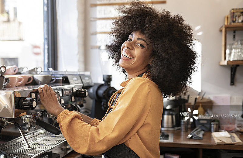 在咖啡馆咖啡机旁，拥有非洲发型的女服务员图片素材