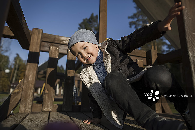 在户外游乐设施上玩耍的微笑男孩图片素材