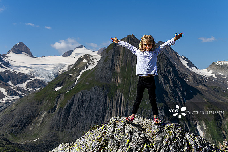在瑞士努费嫩山口岩石上张开双臂的女孩图片素材