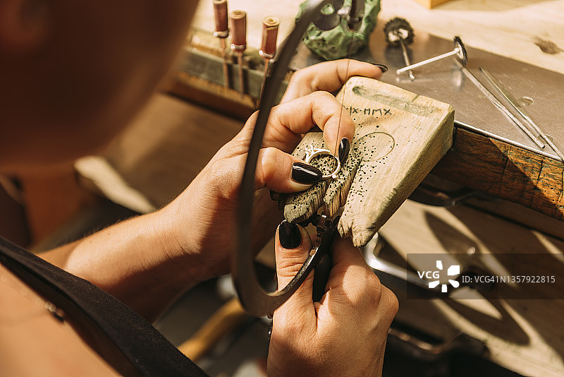 女珠宝商用手锯切割银戒指图片素材