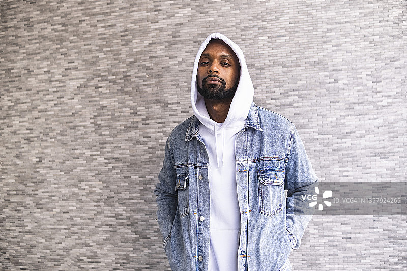 站在墙前，双手插在口袋里的男人图片素材