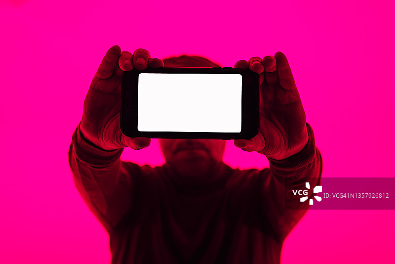 男人展示粉色背景下的智能手机空白屏幕图片素材