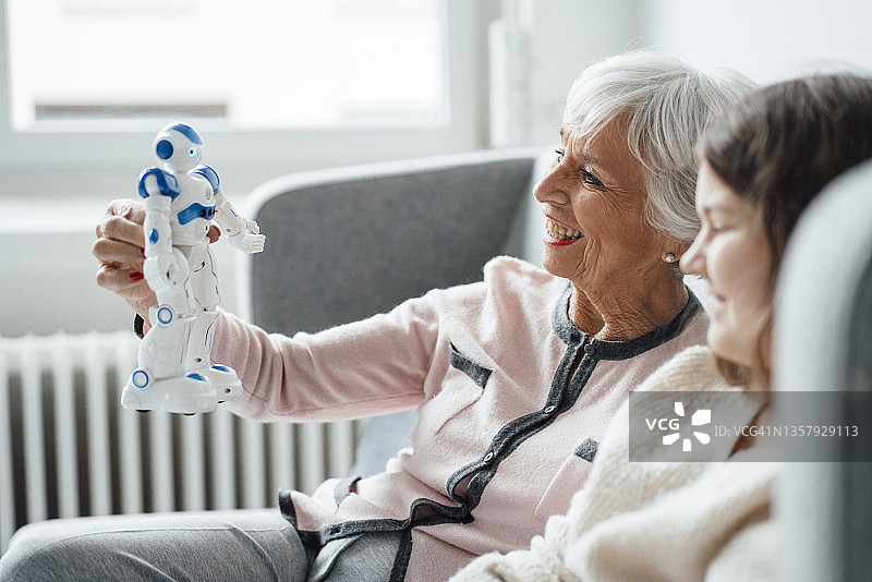 快乐的女人在家抱着女孩的机器人玩具图片素材