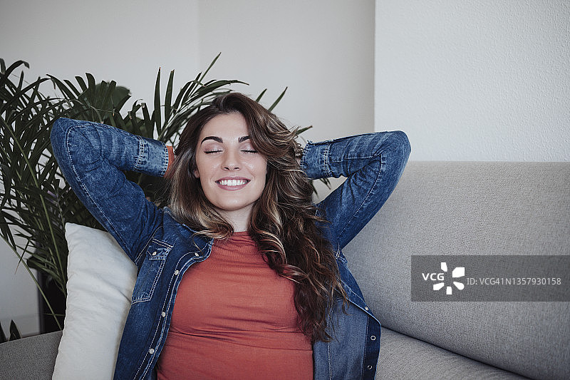 在沙发上放松的微笑闭眼女人图片素材