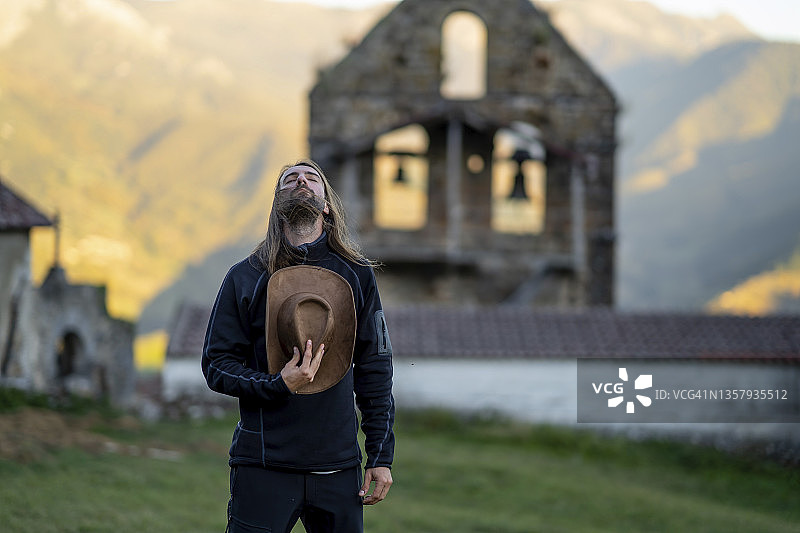 在墓地下仰头手拿帽子的年轻男人图片素材
